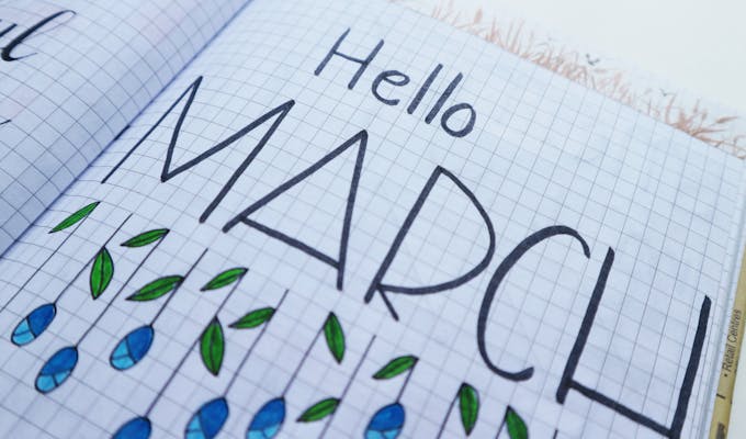 Open notebook with "Hello March" illustration featuring colorful raindrops and leaves.