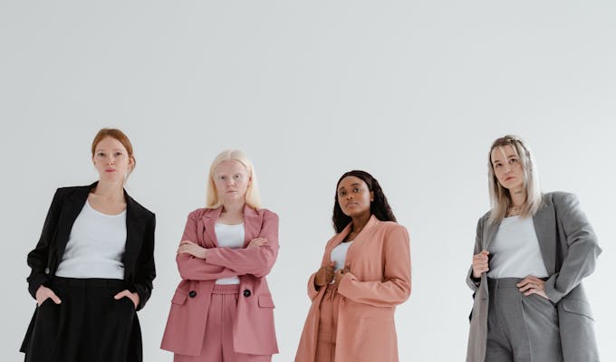 ConfidenceA group of confident businesswomen posing in colorful suits on a white background.