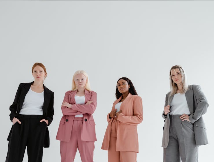 ConfidenceA group of confident businesswomen posing in colorful suits on a white background.