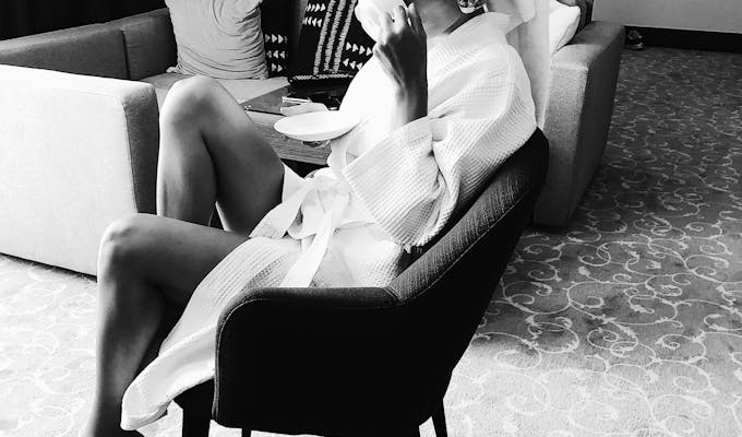 Chic woman in a bathrobe and towel turban, enjoying a drink indoors.