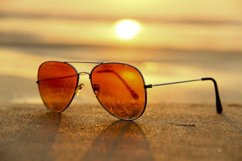 Close-up of sunglasses on a beach during a vibrant sunset, capturing the essence of summer.July 2025 Astrology Forecast