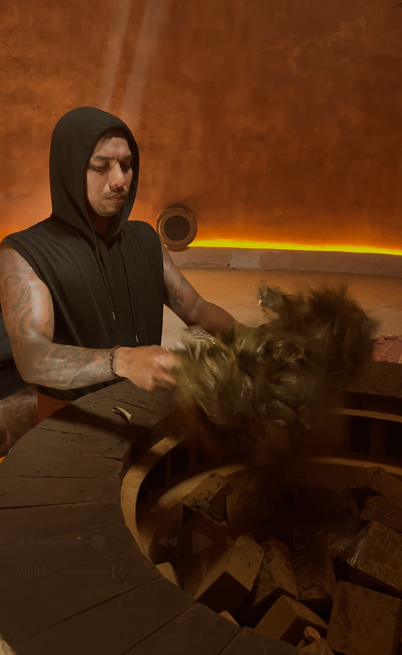 Parenia steam therapist warming a bundle of leaves before treatment, with leaves used later to apply ice-cold water and stimulate the body during the ceremony.