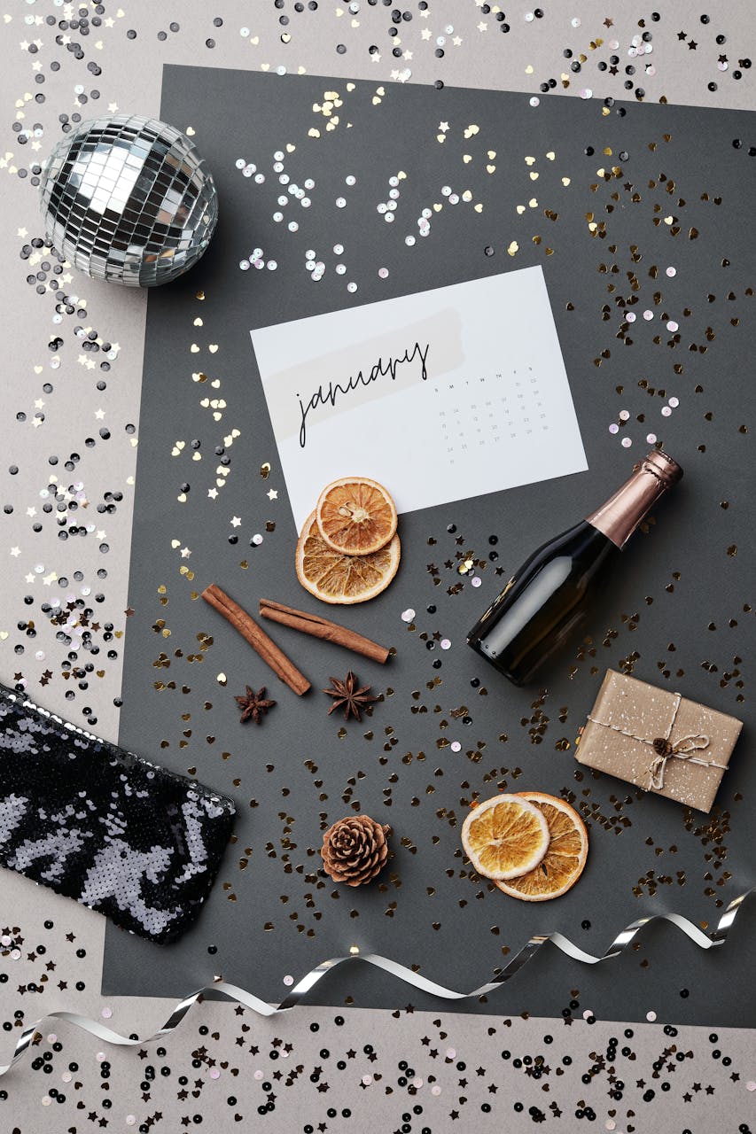 2026 Yearly HoroscopeStylish flat lay with New Year elements: calendar, bottle, gift, spices on a festive background.