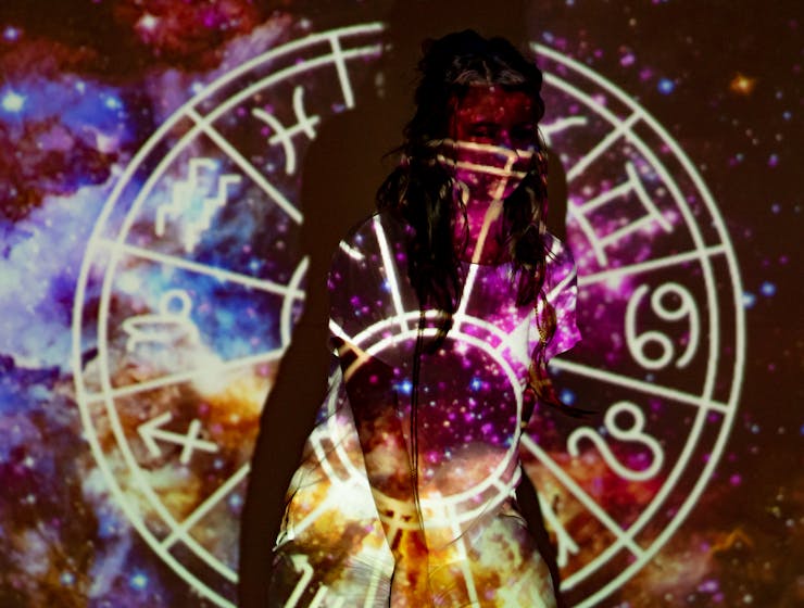 March 2026 HoroscopesA mystical image of a woman enveloped in celestial projections and astrological symbols.