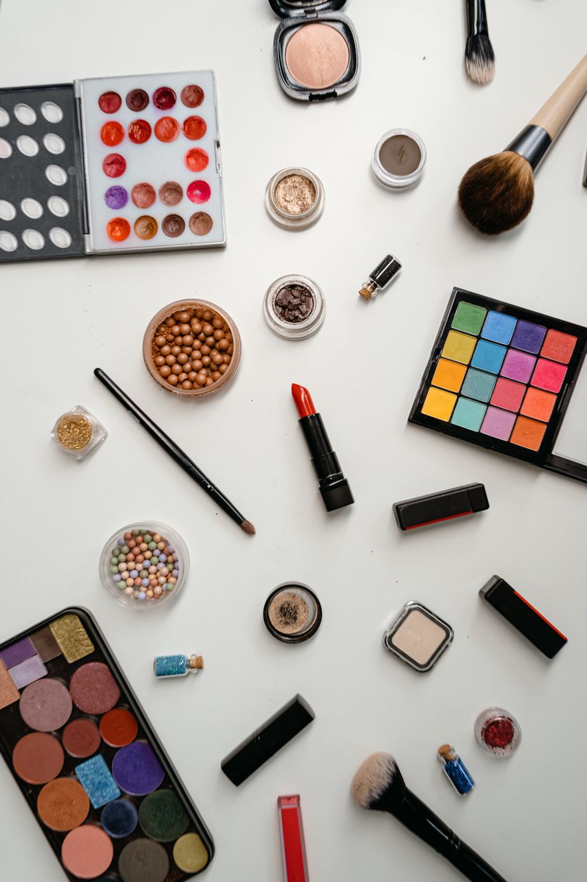 Understanding Makeup EssentialsTop view of a multicolored makeup assortment featuring eyeshadow palettes, brushes, and lipsticks.