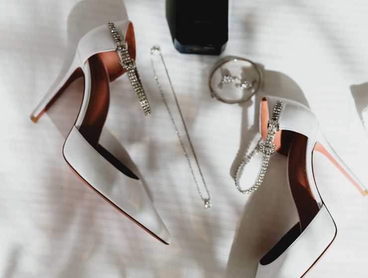 8 Ways to Ensure Accessories and Essentials Won't Ruin Your Look Elegant flat lay of wedding shoes and accessories with perfume, showcasing bridal style.