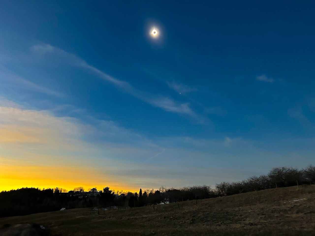 A mesmerizing tableau of a sunset and celestial event over a rural landscape in Burke, Vermont.