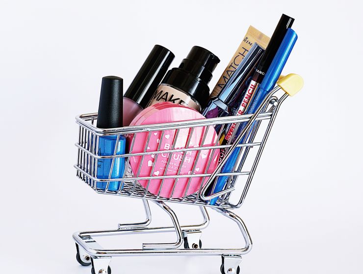 Beauty ShoppingMiniature shopping cart filled with a variety of cosmetics on a white background.