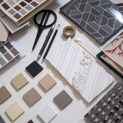A flat lay of a designer's workspace featuring color swatches and material samples for interior design.