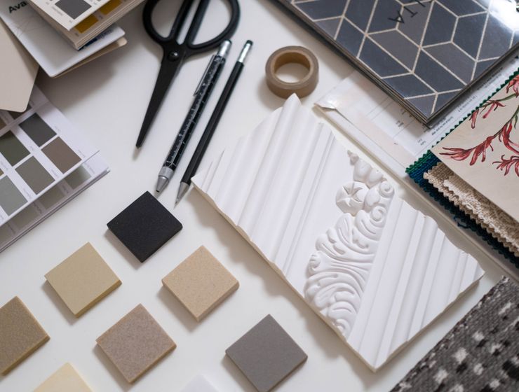 A flat lay of a designer's workspace featuring color swatches and material samples for interior design.