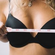 Breast Fat Transfer vs Implants: Pros, Cons and Results Close-up of a woman measuring her bust with tape for the perfect bra fit.